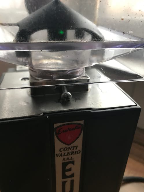 Schraube am Bohnenbehälter der Espressomühle lösen