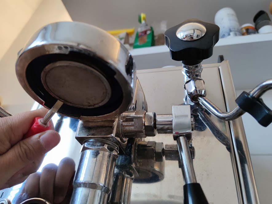 Altes Duschsieb wird mit stumpfem Schraubenzieher herausgehebelt.